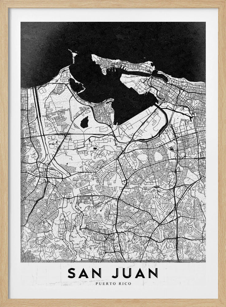 A minimalist black and white map of San Juan, Puerto Rico, shown as a framed poster. The land is depicted in white with intricate black lines for roads and streets, while the surrounding water is a solid, textured black. A white banner at the bottom features the text 'SAN JUAN' in a bold, black, sans-serif font. Artwork