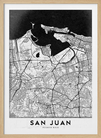 A minimalist black and white map of San Juan, Puerto Rico, shown as a framed poster. The land is depicted in white with intricate black lines for roads and streets, while the surrounding water is a solid, textured black. A white banner at the bottom features the text 'SAN JUAN' in a bold, black, sans-serif font. Artwork