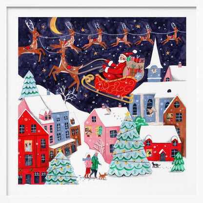 A festive illustration of Santa Claus flying in his sleigh pulled by reindeer over a snowy European-style village at night. The sky is a deep starry blue with a crescent moon, and the houses below are painted in vibrant reds, pinks, and blues, with warm light in the windows. People walk in the snow near decorated Christmas trees. Decor