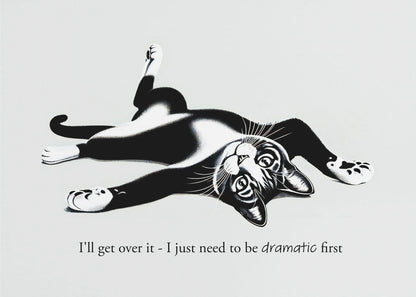 A framed black and white illustration of a tuxedo cat lying playfully on its back. Below the image is the text, 'I'll get over it - I just need to be dramatic first'. Artwork