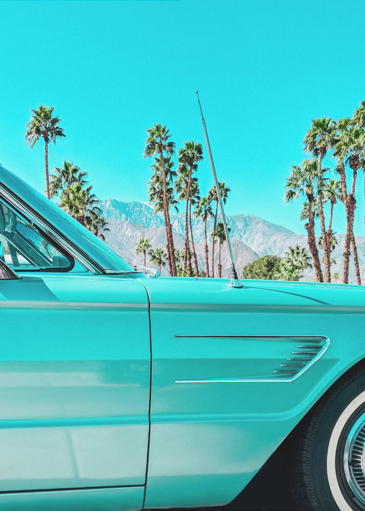 A vibrant, stylized photograph of a vintage turquoise car parked under a clear blue sky, with a row of tall palm trees and distant mountains creating a classic, sunny California scene. Wall Art
