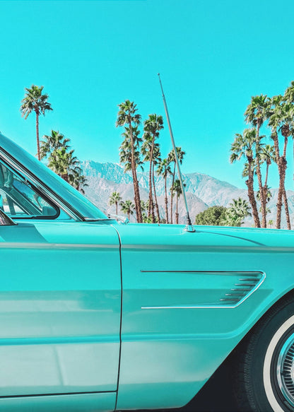 A vibrant, stylized photograph of a vintage turquoise car parked under a clear blue sky, with a row of tall palm trees and distant mountains creating a classic, sunny California scene. Wall Art