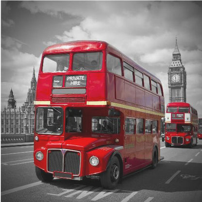 A framed, selective color photograph of a bright red, vintage double-decker bus on a bridge in London. The background, including the Big Ben clock tower, is in black and white, making the red bus stand out. Artwork