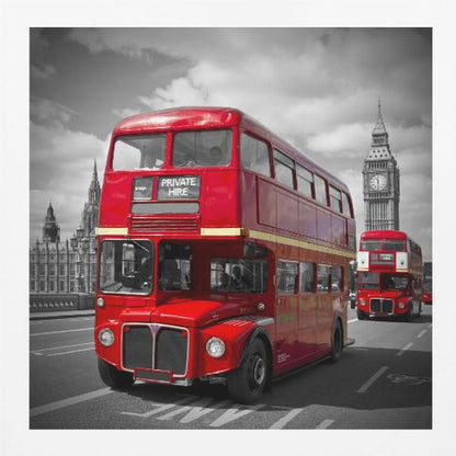 A framed, selective color photograph of a bright red, vintage double-decker bus on a bridge in London. The background, including the Big Ben clock tower, is in black and white, making the red bus stand out. Artwork