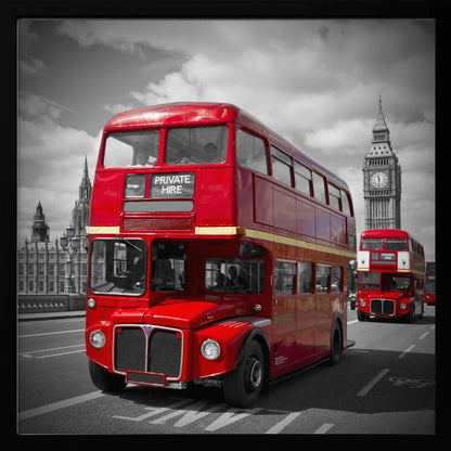 A framed, selective color photograph of a bright red, vintage double-decker bus on a bridge in London. The background, including the Big Ben clock tower, is in black and white, making the red bus stand out. Artwork