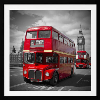 A framed, selective color photograph of a bright red, vintage double-decker bus on a bridge in London. The background, including the Big Ben clock tower, is in black and white, making the red bus stand out. Artwork