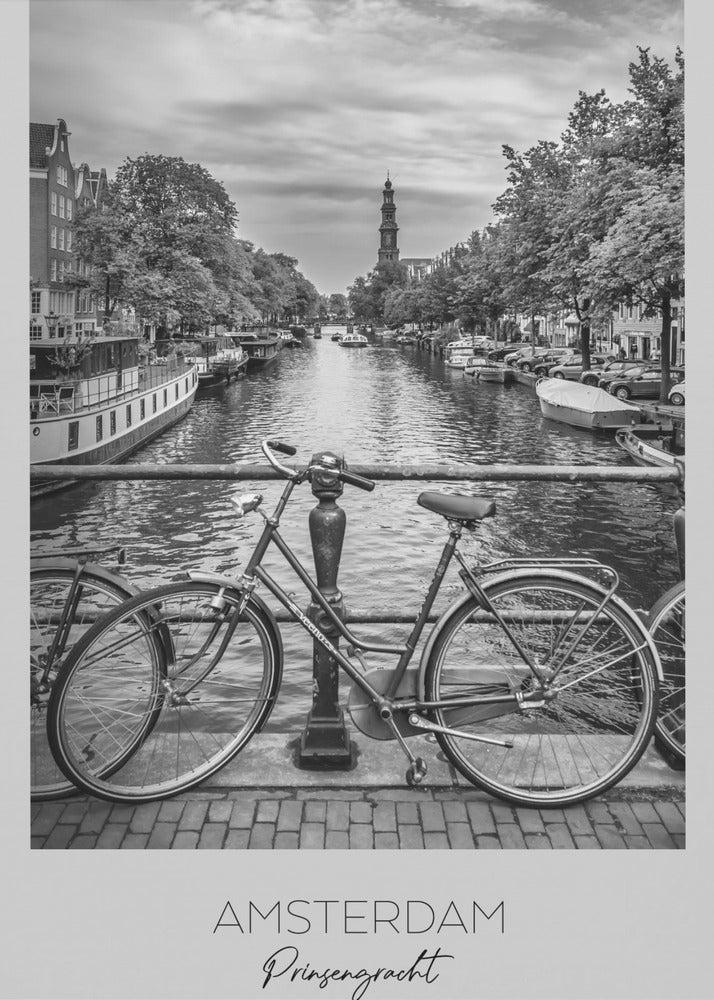 A black and white poster of the Prinsengracht canal in Amsterdam. A bicycle is parked on a bridge in the foreground, overlooking the canal lined with houseboats, trees, and traditional Dutch buildings. The Westerkerk church tower is visible in the distance. The poster has a white border with the words 'AMSTERDAM', 'Prinsengracht', and 'NEDERLAND' at the bottom. Poster