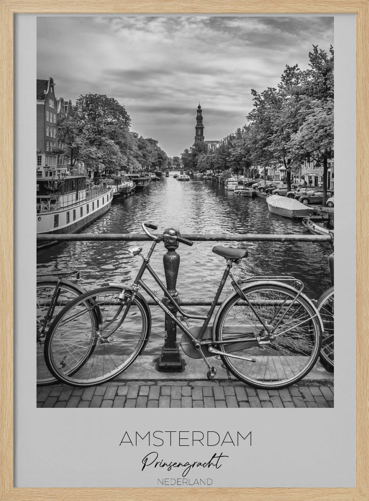 A black and white poster of the Prinsengracht canal in Amsterdam. A bicycle is parked on a bridge in the foreground, overlooking the canal lined with houseboats, trees, and traditional Dutch buildings. The Westerkerk church tower is visible in the distance. The poster has a white border with the words 'AMSTERDAM', 'Prinsengracht', and 'NEDERLAND' at the bottom. Poster