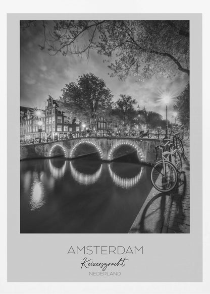 A black and white poster of Amsterdam's Keizersgracht canal at night. An arched bridge with glowing lights is the centerpiece, its reflection shimmering on the dark water. Bicycles are parked along the bridge and in the foreground on a cobblestone path. Classic canal houses and trees line the background under a dramatic, cloudy sky. The image is framed with text below reading 'AMSTERDAM Keizersgracht NEDERLAND'. Artwork