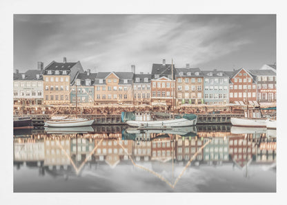 A framed, color-selective photograph of the Nyhavn harbor in Copenhagen. A row of colorful 17th and 18th-century townhouses lines the waterfront, with their warm lights and facades reflecting in the calm canal. The sky and parts of the water are in black and white, making the colored buildings stand out. Several boats are moored along the quay. Decor