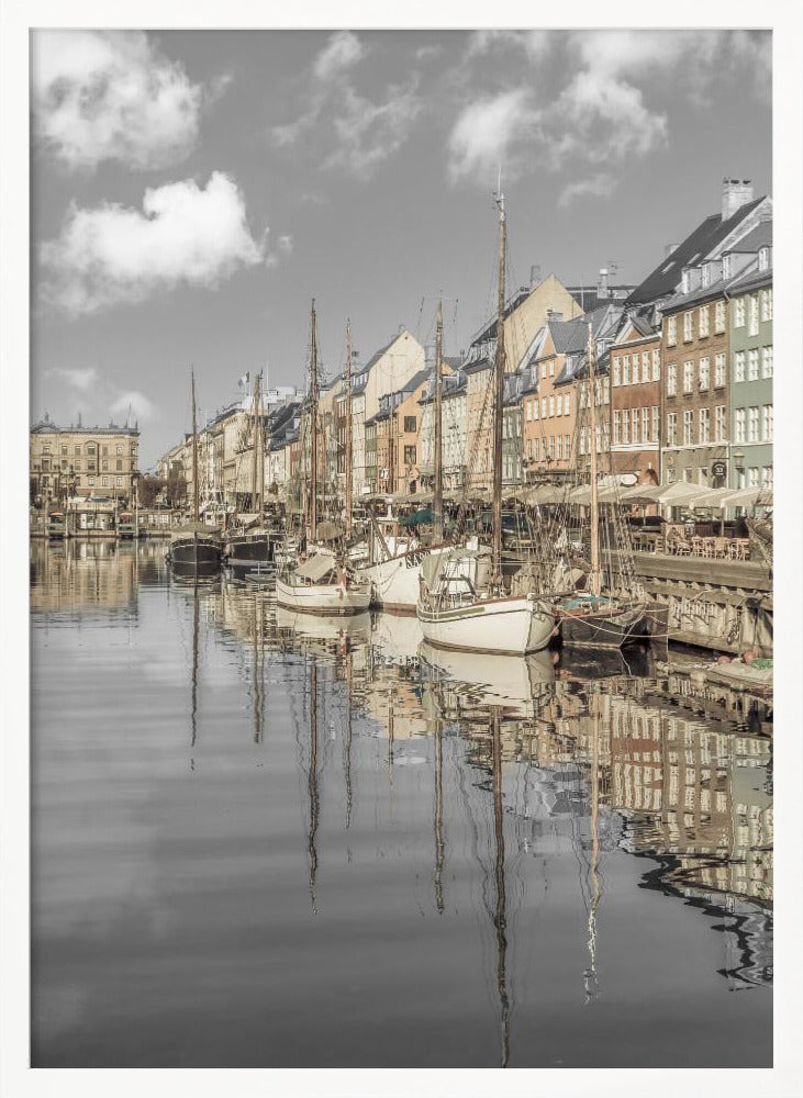 A muted, desaturated photograph of the Nyhavn harbor in Copenhagen. Old-fashioned sailboats are moored along the canal in front of a row of colorful historic buildings. The boats, buildings, and a cloudy sky are perfectly reflected in the calm water. Wall Art