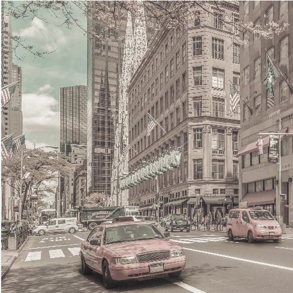 A framed photograph of a busy New York City street with a vintage, sepia-toned filter. Two cars, one in the foreground and one in the midground, are selectively colored a dusty pink, contrasting with the muted tones of the surrounding skyscrapers, American flags, and pedestrians. The sky is a pale teal color. Poster