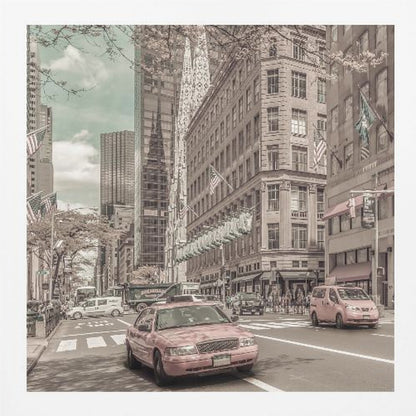 A framed photograph of a busy New York City street with a vintage, sepia-toned filter. Two cars, one in the foreground and one in the midground, are selectively colored a dusty pink, contrasting with the muted tones of the surrounding skyscrapers, American flags, and pedestrians. The sky is a pale teal color. Poster