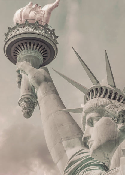 A low-angle, close-up photograph of the Statue of Liberty with a vintage color treatment. The shot captures her profile, crown, and her arm holding the torch aloft against a muted, cloudy sky, all enclosed in a thin black frame. Poster