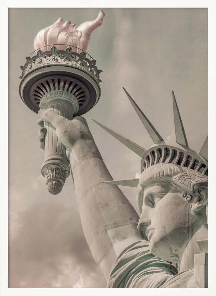 A low-angle, close-up photograph of the Statue of Liberty with a vintage color treatment. The shot captures her profile, crown, and her arm holding the torch aloft against a muted, cloudy sky, all enclosed in a thin black frame. Poster