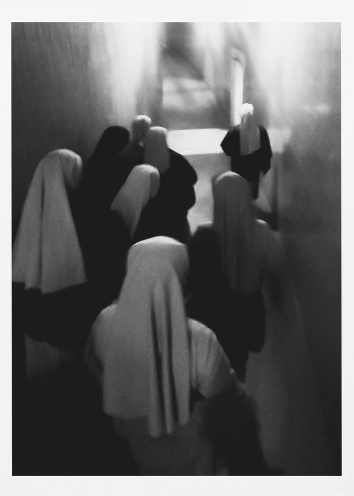 A mysterious black and white photograph captures a group of robed figures, possibly nuns, from above as they walk down a dark, narrow corridor. The image is blurred, creating a ghostly, ethereal atmosphere as the figures' white head coverings stand out against the deep shadows. Artwork