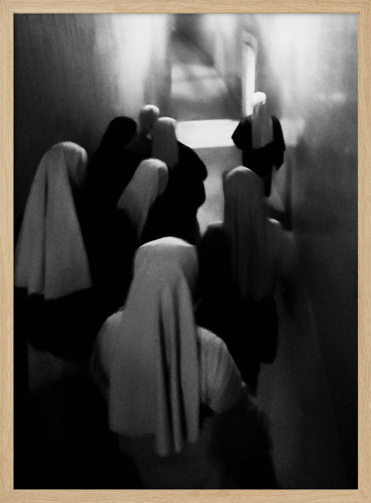 A mysterious black and white photograph captures a group of robed figures, possibly nuns, from above as they walk down a dark, narrow corridor. The image is blurred, creating a ghostly, ethereal atmosphere as the figures' white head coverings stand out against the deep shadows. Artwork