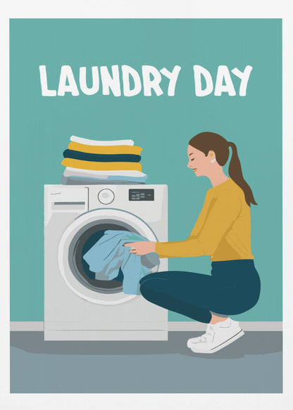A framed illustration poster with the words 'LAUNDRY DAY' in white at the top. A woman with brown hair in a ponytail, wearing a yellow top and blue pants, crouches to load blue clothes into a white front-loading washing machine. A stack of folded laundry sits atop the machine against a teal background. Print