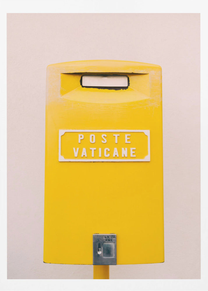 A close-up, front-view photograph of a vibrant yellow Vatican City mailbox against a plain beige wall, enclosed in a thin black frame. The words 'POSTE VATICANE' are printed in white on the front. Artwork