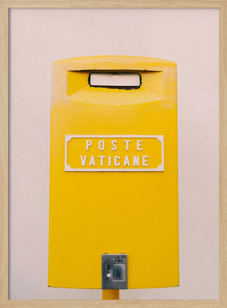 A close-up, front-view photograph of a vibrant yellow Vatican City mailbox against a plain beige wall, enclosed in a thin black frame. The words 'POSTE VATICANE' are printed in white on the front. Artwork