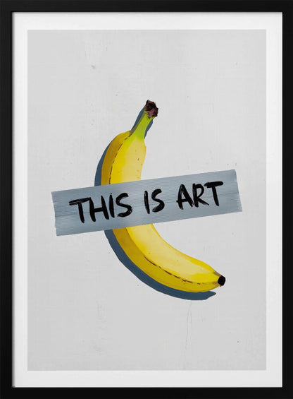 A framed artwork depicting a single yellow banana taped to a white wall with a grey strip of tape that reads 'THIS IS ART' in black marker-style font. Artwork