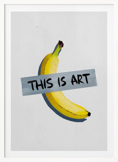 A framed artwork depicting a single yellow banana taped to a white wall with a grey strip of tape that reads 'THIS IS ART' in black marker-style font. Artwork