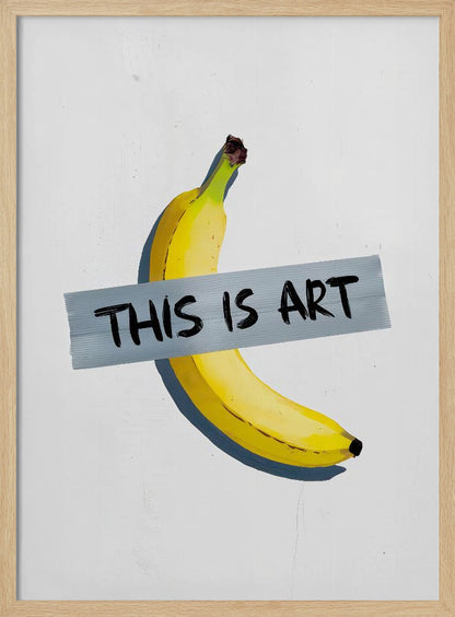 A framed artwork depicting a single yellow banana taped to a white wall with a grey strip of tape that reads 'THIS IS ART' in black marker-style font. Artwork