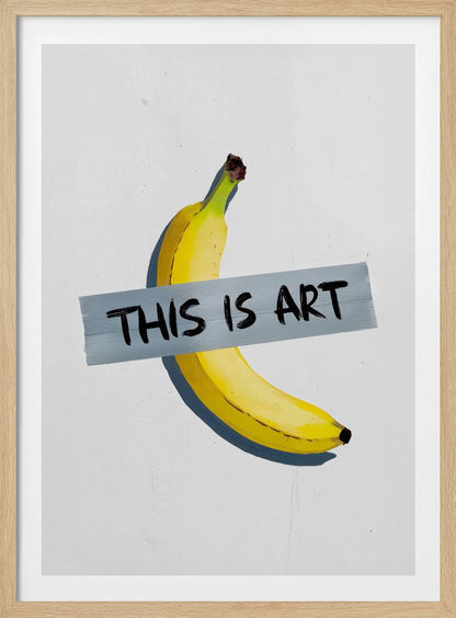 A framed artwork depicting a single yellow banana taped to a white wall with a grey strip of tape that reads 'THIS IS ART' in black marker-style font. Artwork