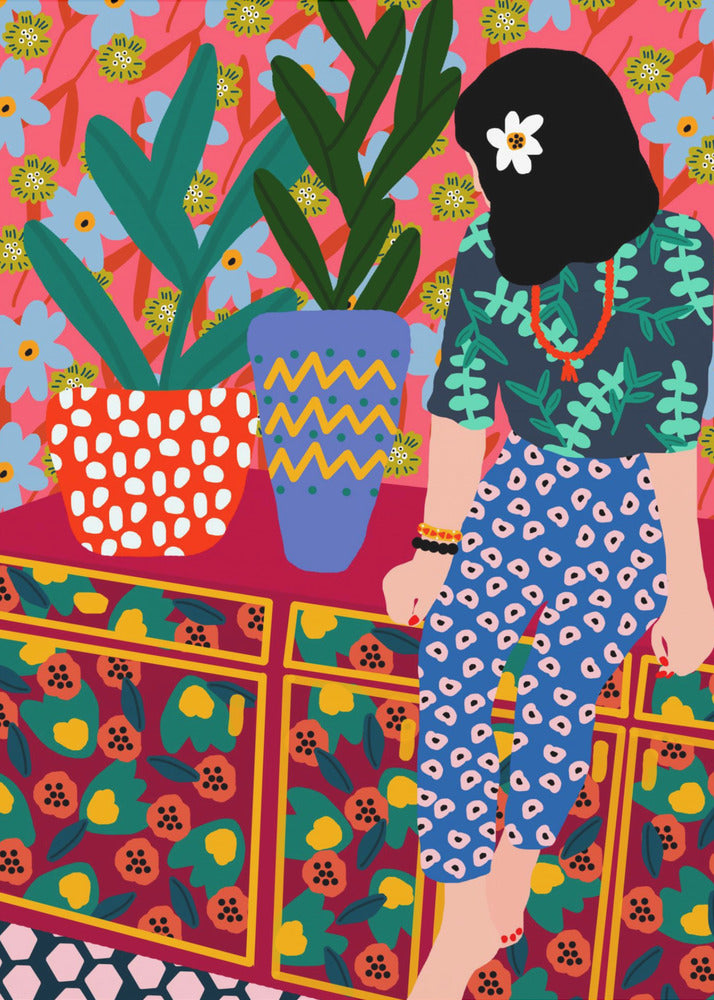 A colorful, maximalist illustration of a woman with black hair and a flower, sitting on a patterned cabinet. She wears a dark blue shirt with green leaves and blue pants with white circles. Next to her are two potted plants in brightly patterned pots, set against a pink and blue floral wallpaper. Poster
