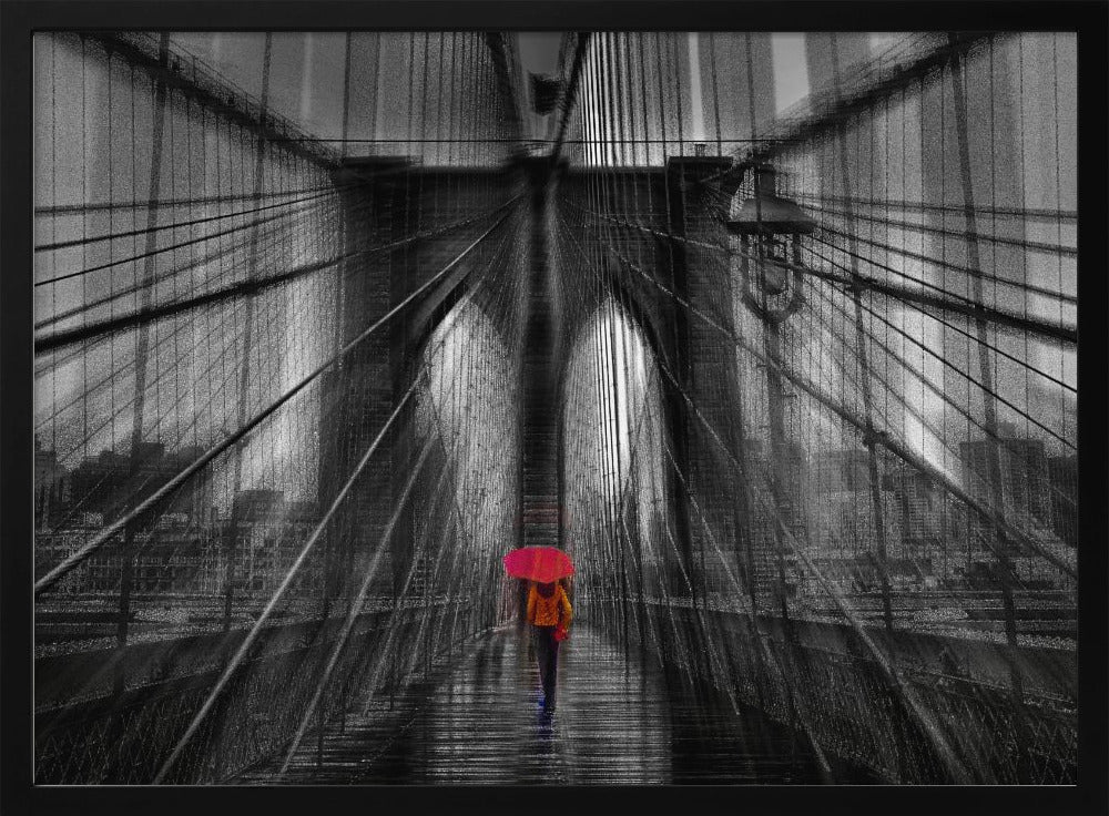 A motion-blurred, black and white photo of the Brooklyn Bridge with a person holding a bright red umbrella walking down the center. The selective color makes the red umbrella the focal point against the dramatic, almost abstract lines of the bridge's cables and arches on a wet, reflective walkway. The image is presented in a silver frame. Wall Art