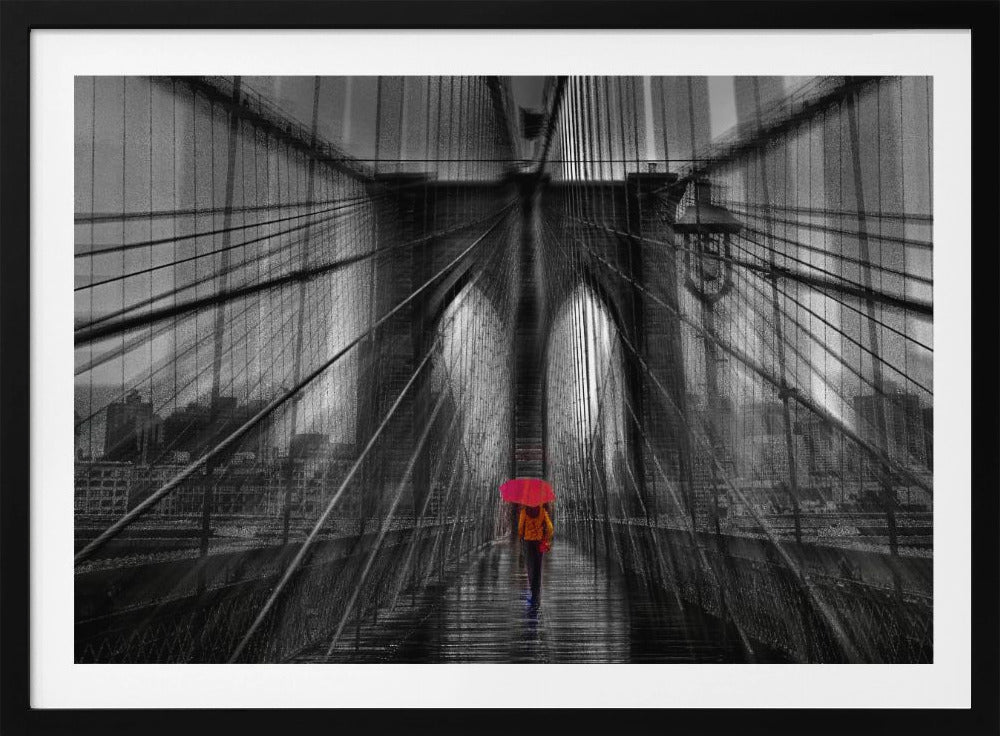 A motion-blurred, black and white photo of the Brooklyn Bridge with a person holding a bright red umbrella walking down the center. The selective color makes the red umbrella the focal point against the dramatic, almost abstract lines of the bridge's cables and arches on a wet, reflective walkway. The image is presented in a silver frame. Wall Art