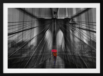 A motion-blurred, black and white photo of the Brooklyn Bridge with a person holding a bright red umbrella walking down the center. The selective color makes the red umbrella the focal point against the dramatic, almost abstract lines of the bridge's cables and arches on a wet, reflective walkway. The image is presented in a silver frame. Wall Art