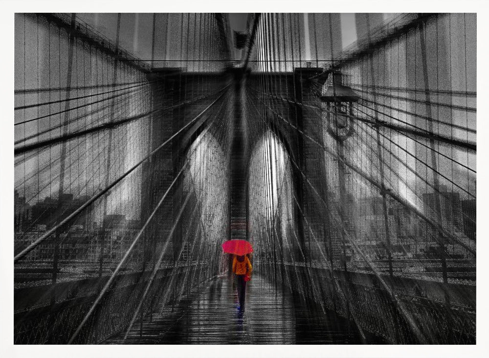 A motion-blurred, black and white photo of the Brooklyn Bridge with a person holding a bright red umbrella walking down the center. The selective color makes the red umbrella the focal point against the dramatic, almost abstract lines of the bridge's cables and arches on a wet, reflective walkway. The image is presented in a silver frame. Wall Art