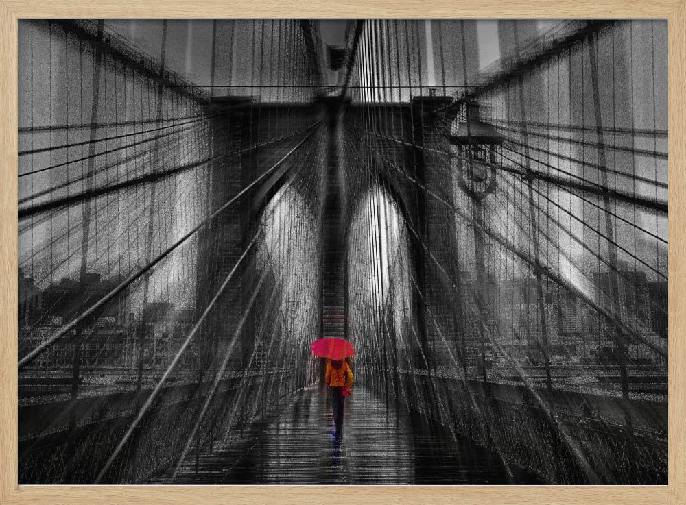 A motion-blurred, black and white photo of the Brooklyn Bridge with a person holding a bright red umbrella walking down the center. The selective color makes the red umbrella the focal point against the dramatic, almost abstract lines of the bridge's cables and arches on a wet, reflective walkway. The image is presented in a silver frame. Wall Art
