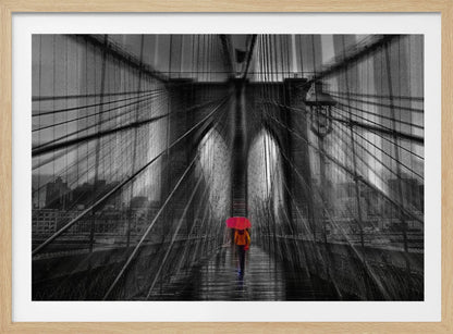 A motion-blurred, black and white photo of the Brooklyn Bridge with a person holding a bright red umbrella walking down the center. The selective color makes the red umbrella the focal point against the dramatic, almost abstract lines of the bridge's cables and arches on a wet, reflective walkway. The image is presented in a silver frame. Wall Art