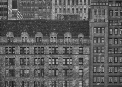 A dense, black and white photograph of various city buildings packed closely together. The image highlights the contrasting architectural styles, from an older stone building with a dark roof in the foreground to taller brick and modern glass buildings in the background, creating a geometric pattern of windows and textures. Decor
