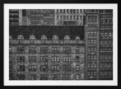 A dense, black and white photograph of various city buildings packed closely together. The image highlights the contrasting architectural styles, from an older stone building with a dark roof in the foreground to taller brick and modern glass buildings in the background, creating a geometric pattern of windows and textures. Decor