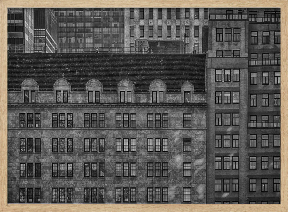 A dense, black and white photograph of various city buildings packed closely together. The image highlights the contrasting architectural styles, from an older stone building with a dark roof in the foreground to taller brick and modern glass buildings in the background, creating a geometric pattern of windows and textures. Decor