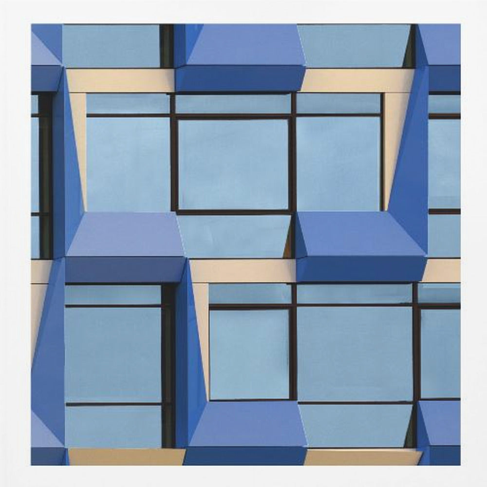 A framed abstract architectural photograph showing a repeating pattern of a modern building's facade. The image features geometric, three-dimensional blue elements surrounding light blue windows with black frames, all set against horizontal cream-colored bands. The entire piece is presented within a light wood frame. Print