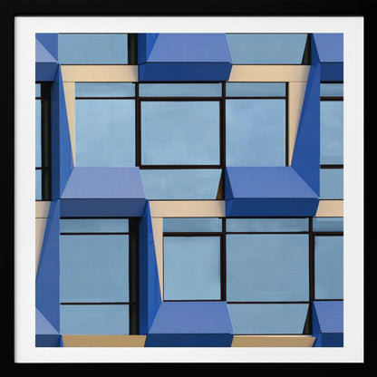 A framed abstract architectural photograph showing a repeating pattern of a modern building's facade. The image features geometric, three-dimensional blue elements surrounding light blue windows with black frames, all set against horizontal cream-colored bands. The entire piece is presented within a light wood frame. Print