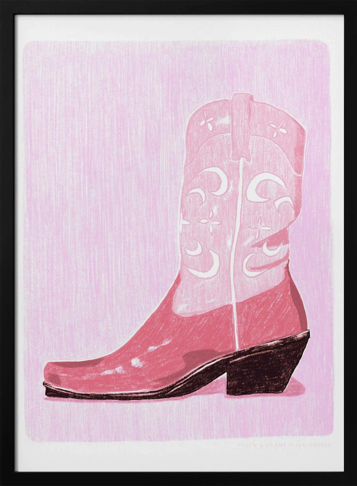 A framed art print of a pink cowboy boot against a light pink, textured background. The boot is illustrated in a block-print style with shades of pink, white decorative inlay patterns of moons and stars, and a dark brown heel and sole. Decor