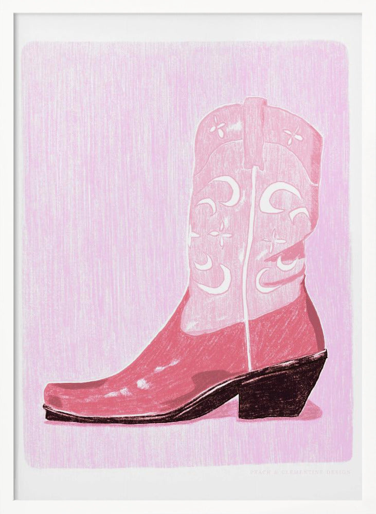 A framed art print of a pink cowboy boot against a light pink, textured background. The boot is illustrated in a block-print style with shades of pink, white decorative inlay patterns of moons and stars, and a dark brown heel and sole. Decor