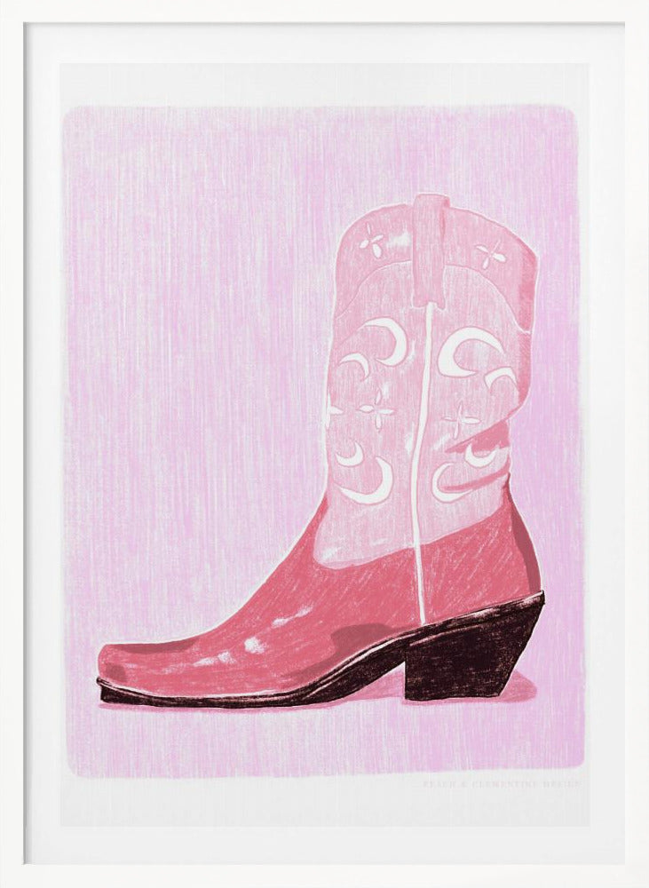 A framed art print of a pink cowboy boot against a light pink, textured background. The boot is illustrated in a block-print style with shades of pink, white decorative inlay patterns of moons and stars, and a dark brown heel and sole. Decor