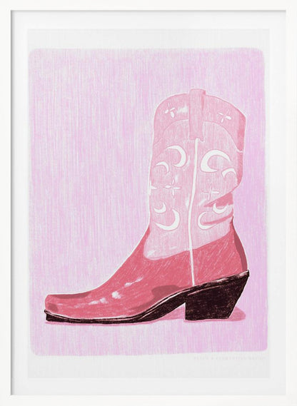 A framed art print of a pink cowboy boot against a light pink, textured background. The boot is illustrated in a block-print style with shades of pink, white decorative inlay patterns of moons and stars, and a dark brown heel and sole. Decor