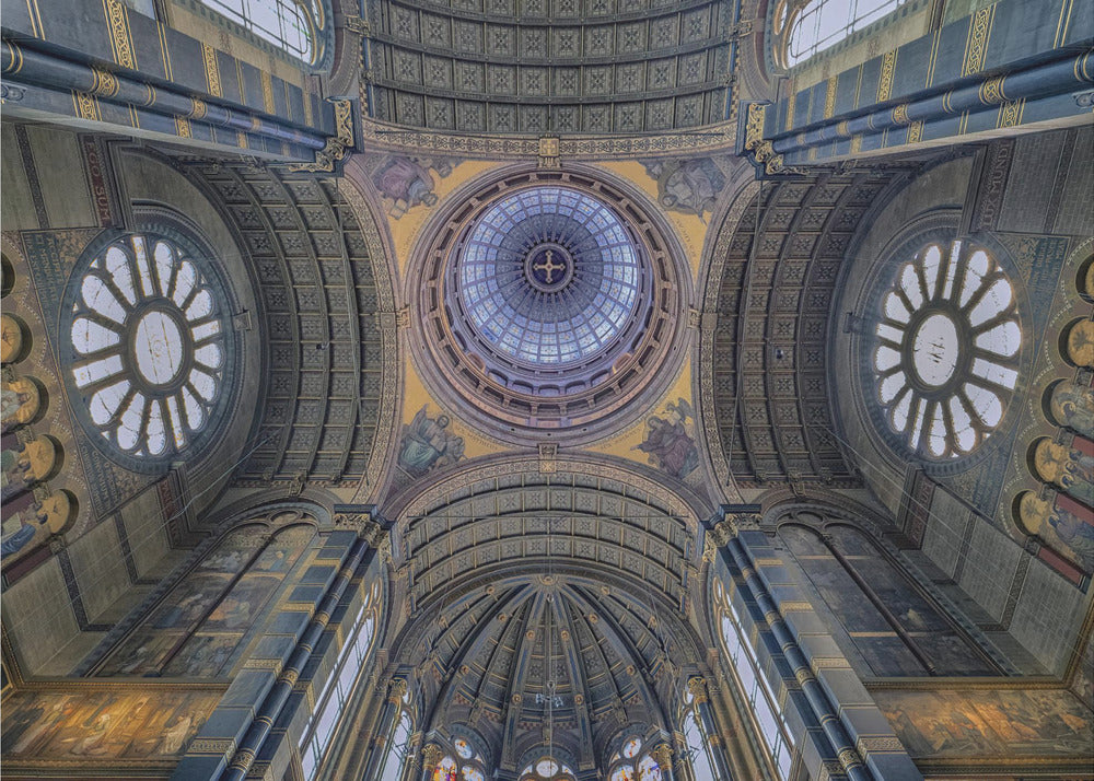 An upward-looking view of the highly ornate vaulted ceiling of a grand cathedral, featuring a central glass dome, large rose windows, and intricate gold and blue details, all framed in silver. Poster