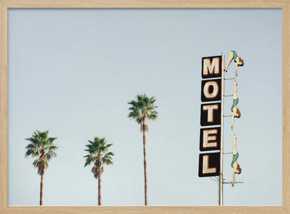 A minimalist photograph featuring three tall palm trees and a vertical black and white 'MOTEL' sign against a pale blue sky. Affixed to the sign's pole are several figures of women in green swimsuits, posed as if diving in a synchronized formation. Poster