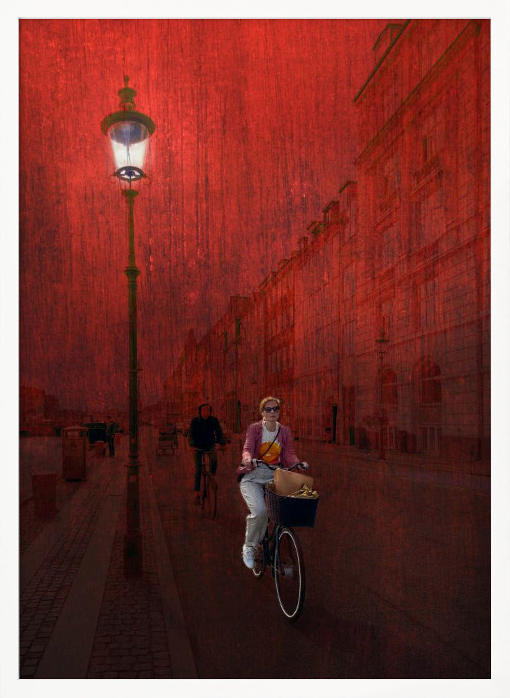 A surreal artistic image of a city street bathed in a textured red light. A woman rides a bicycle with a basket towards the viewer, while another cyclist is in the background. A tall, ornate lamppost is lit on the left side of the cobblestone street. Wall Art