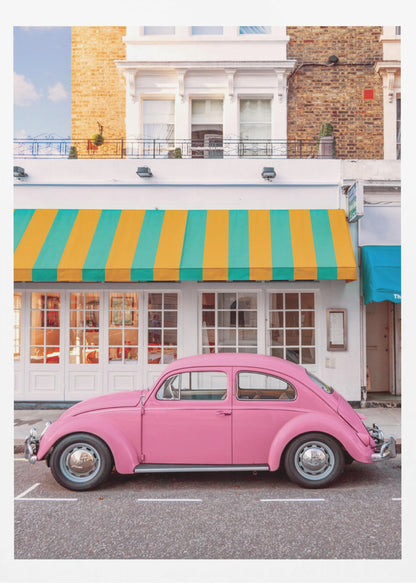 A vibrant, eye-level photograph of a vintage pink Volkswagen Beetle parked on a city street in front of a charming white storefront with a bold yellow and teal striped awning. Wall Art