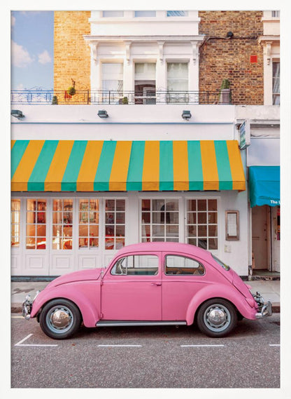 A vibrant, eye-level photograph of a vintage pink Volkswagen Beetle parked on a city street in front of a charming white storefront with a bold yellow and teal striped awning. Wall Art