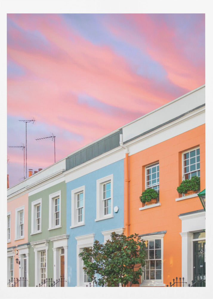 A row of colorful pastel townhouses in shades of orange, blue, green, and pink, viewed from a low angle against a dramatic, cloudy pink and purple sunset sky. Poster
